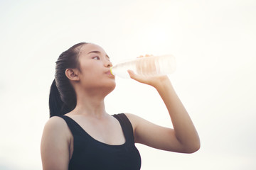 Beautiful young fitness woman drinking water after running exercise