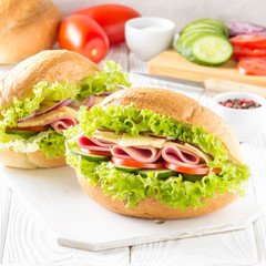 Closed sandwich in bun with ham, cheese, lettuce, tomato, cucumber, red onion. Delicious breakfast, classic lunch