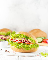 Closed sandwich in bun with ham, cheese, lettuce, tomato, cucumber, red onion. Delicious breakfast, classic lunch