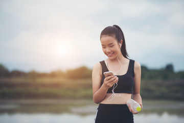 Fitness woman in earphones listening music during her workout and exercise in the park