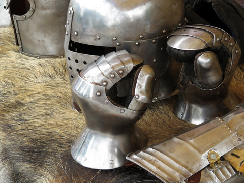 Medieval helmets and gloves on a bearskin rug. Armor of middle ages, knightly equipment, armory forge