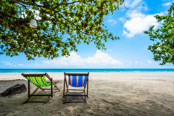 Tropical tree and beach chair at white sand beach and blue sea