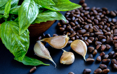 Fresh basil in the wooden bowl, cloves of garlic and pine nuts
