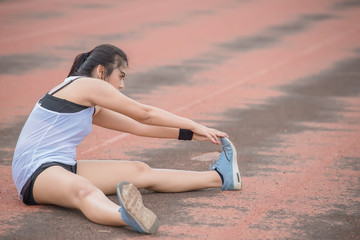 Fototapeta na wymiar Asian sporty woman stretching body breathing fresh air in the park,Thailand people,Fitness and exercise concept,Jogging in the track