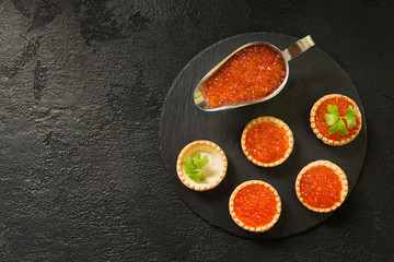 Red caviar in tartlets on a black background