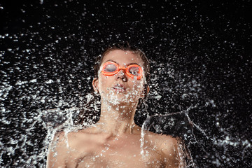Fototapeta na wymiar portrait of woman in swimming goggles swilled with water isolated on black