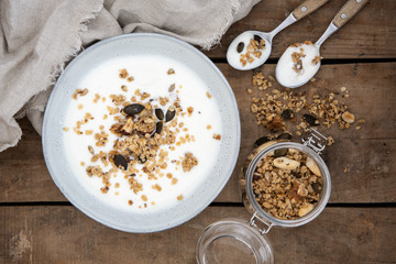 Schüssel mit Joghurt und Granola aus Haferflocken, Nüssen, Leinsamen, Sonnenblumenkernen und...