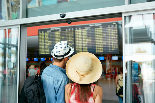 People Travel In Airport. Couple Looking At Flight Board