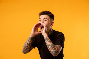 Do not miss. Young casual man shouting. Shout. Crying emotional man screaming on studio background. male half-length portrait. Human emotions, facial expression concept. Trendy colors