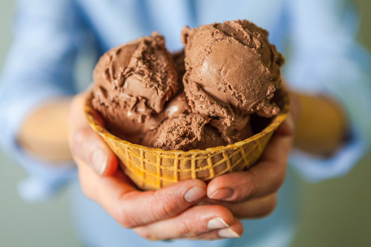 Closeup of Hands Holding a Waffle Bowl with Chocolate Ice Cream
