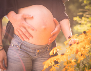 Schwangere junge Frau mit Babybauch, gelbe Blumen
