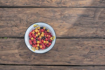 Pile of Fresh Raspberries in the Bowl on a wooden background.