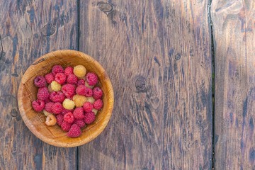 Pile of Fresh Raspberries in the Bowl on a wooden background.