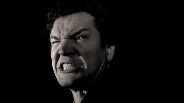 Man scary screaming expression. A monster of a man scares with a loud scream in film noir black and white. Rage faced man yells in anger.