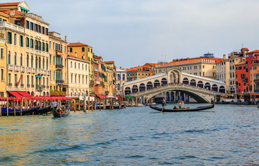 Gondolas and boats by the Rialto Bridge on Grand Canal of Venice Italy