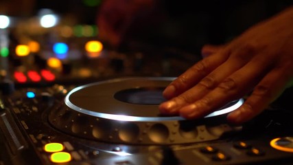 DJ hands spinning turntable. Male professional Disc Jockey spins CDJ turntable with his hands to skip the music. Scratching tunes on music mixer.
