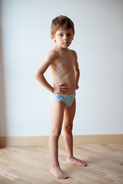 strong healthy small caucasian child in shorts showing body shape indoors