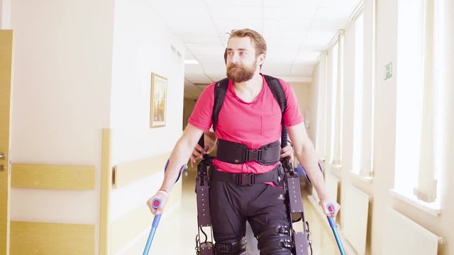 Young disable man walking in the robotic exoskeleton in the rehabilitation clinic.