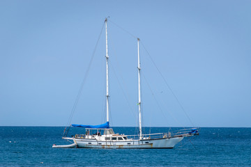 Old white yacht sailing the calm ocean on sunny day in the Caribbean