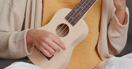 Fototapeta premium Woman play a song ukulele at home
