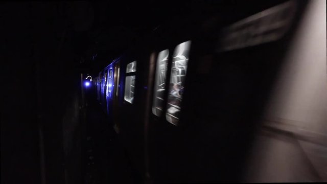 Loop of subway moving through dark tunnel. Loopable New York City inside subway tunnel with blue traffic signal light. Blurry train moves through underground railway in restricted area for people.