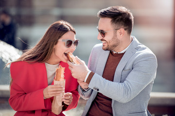 Young couple eating sandwich outdoors