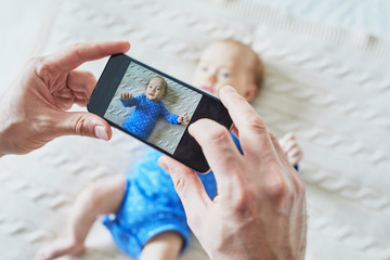 Father taking photo of his daughter or son with mobile phone