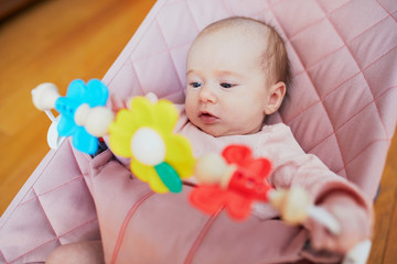 Baby girl playing with toys in bouncer