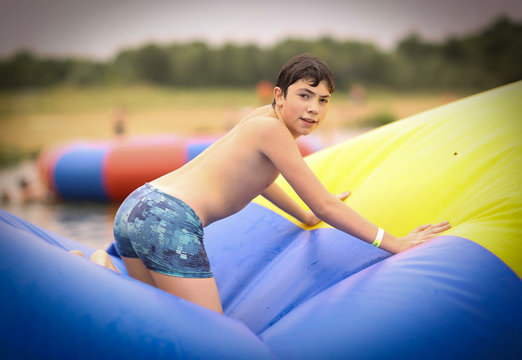 Teenager Boy In Open Air Amusement Aquapark Jump On Trampoline