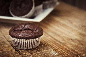 Chocolate muffins. Homemade chocolate muffins with spices on wooden background. Sweet dessert. Dark photo. Toned.