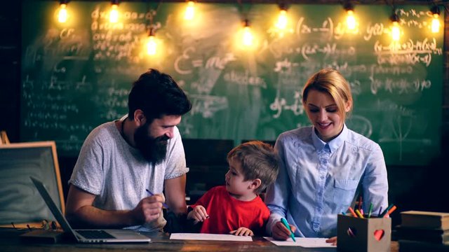 Father, mother and their son paint in a school class. Learning concept. School children in uniform. Teacher in classroom. Teacher and student. Back to school.