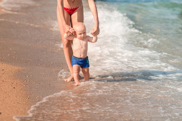 Fototapeta premium Cute little baby walking along the seaside with his sister
