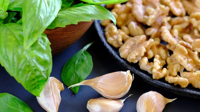 Human hand puts several cloves of garlic on the table. Ingredients for a sauce pesto. Dark background. Macro shot.