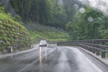 Regennasse Fahrbahn und Regentropfen auf einer Auto Windschutzscheibe