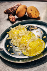 Round shaped homemade stuffed pasta dressed with, parmesan cream, shallot and pine nuts.