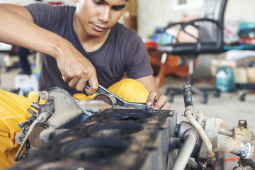 The car repairer is checking the car for maintenance. People who work on cars in the garage do their own homework. Check / inspect the engine for trouble