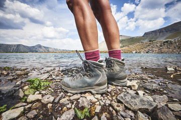 A young woman wearing hiking boots and trekking around an alpine mountain lake