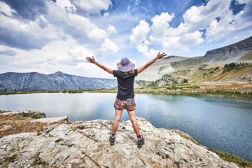 Obraz premium a young woman standing on top of a mountain with arms raised in excitement