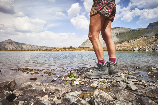 A young woman wearing hiking boots and trekking around an alpine mountain lake