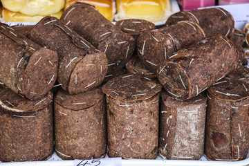Romanian traditional cheese wrapped in fir bark and wheels of smoked cheese on one of the agricultural markets region Wallachia, Romania
