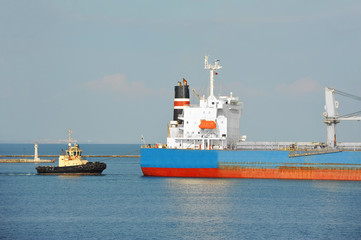 Tugboat assisting bulk cargo ship