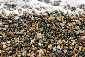 waves of the blue sea on a pebble beach. small pebble stones by the sea.
