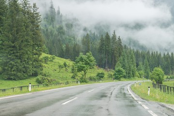 Regennasse Fahrbahn und Regentropfen auf einer Auto Windschutzscheibe