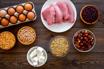 Healthy food. Products rich protein and fiber. Legumes, nuts, low-fat cheese, meet, eggs. Raw beans, chickpeas, lentil, almond, hazelnut on dark wooden background top view