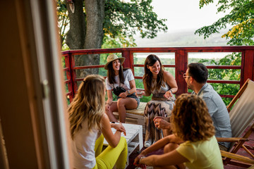 Group of friends laughing while sitting on the terrace with a beautiful view.