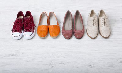 Collection of women's shoes on white wooden background