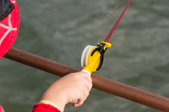 A child's hand is fishing on a small fishing rod. Ozernaya fishing.