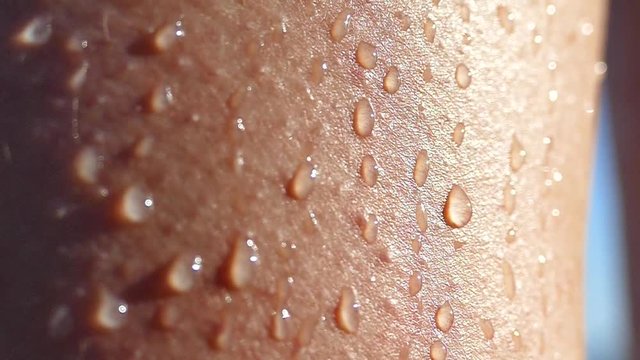 Drops of water on a wet tanned body. A hand slides over the bare shoulder of a woman.
