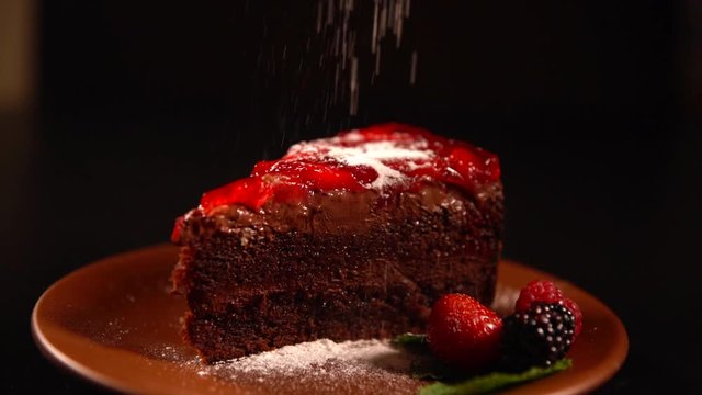 Sprinkling castor sugar on a chocolate cake