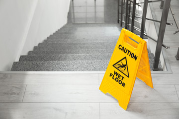 Safety sign with phrase Caution wet floor near stairs - obrazy, fototapety, plakaty